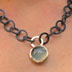 Eine grob geschmiedete Ösenkette trägt einen großen Mondstein-Cabochon